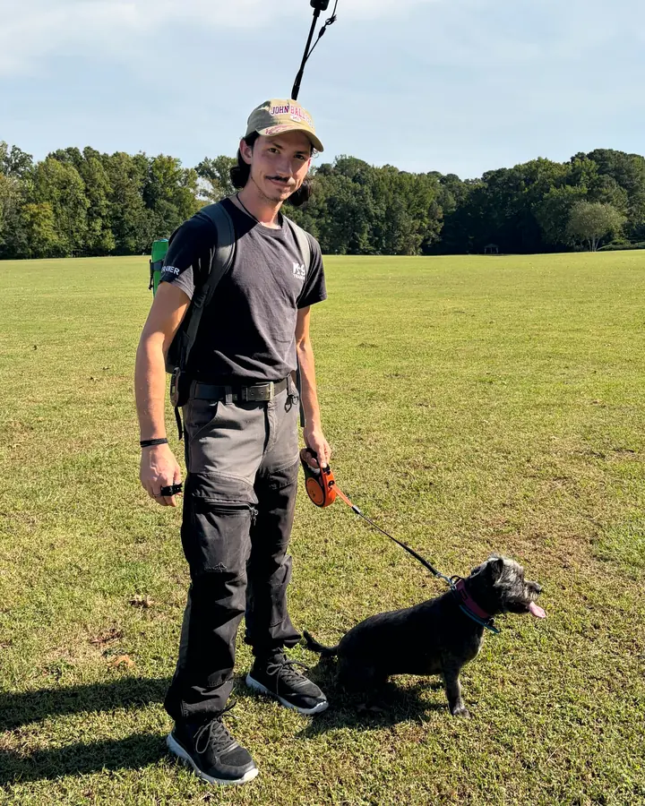 Christian Scharphorn standing in a park with a small dark dog on a leash