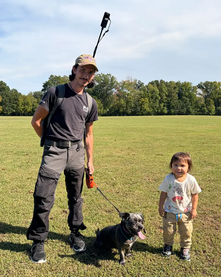 Christian Scharphorn with his young daughter and a small dark dog on a leash in a park