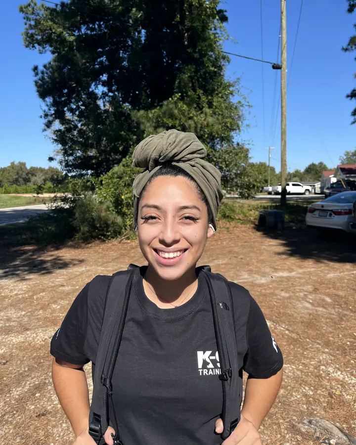 Gemma, who manages Angier K9’s main line, smiling outdoors in an Angier K9 shirt